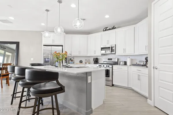 a kitchen with stainless steel appliances granite countertop a stove a sink dishwasher a refrigerator and white cabinets with wooden floor