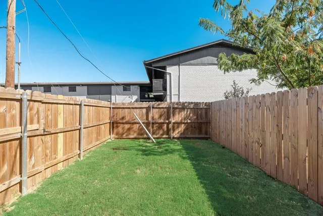a view of a backyard with wooden fence and large trees