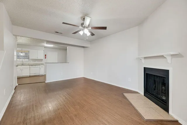 an empty room with wooden floor fireplace and windows