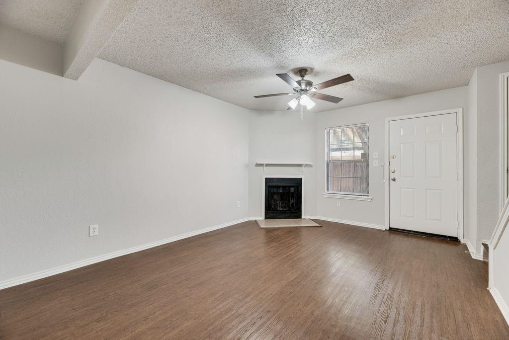 648 South Rogers Road, Unit 648 Irving, TX 75060 - Photo 5 of 20 an empty room with windows fireplace and a ceiling fan