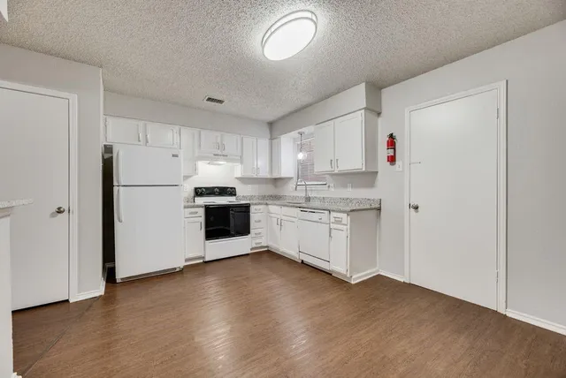 a kitchen with granite countertop white cabinets and white appliances