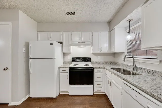 a kitchen with a stove a sink and white stainless steel appliances