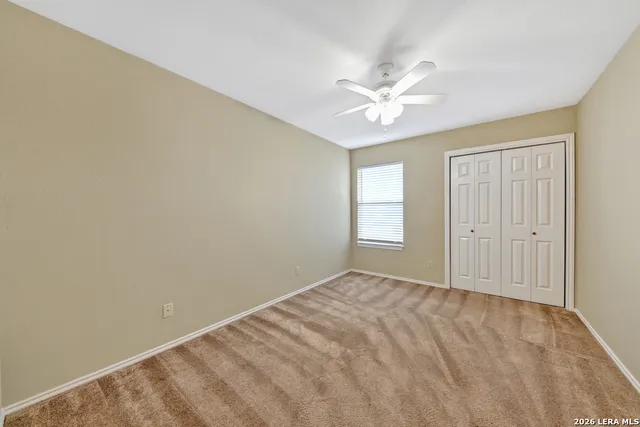a view of an empty room with window and a ceiling fan