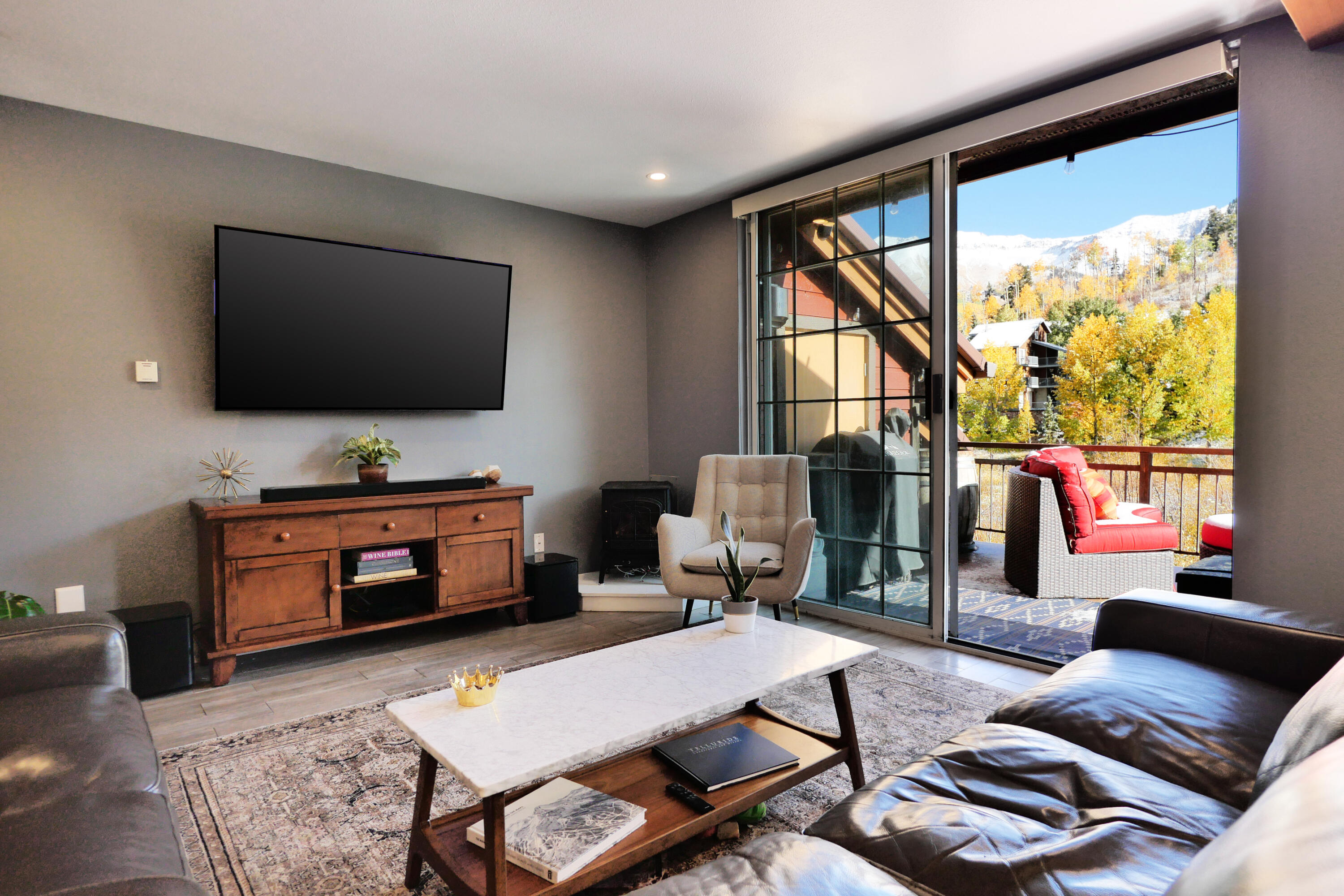 302 Adams Ranch Road, Unit 6 Mountain Village, CO 81435 - Photo 8 of 45 a living room with furniture a flat screen tv and a floor to ceiling window