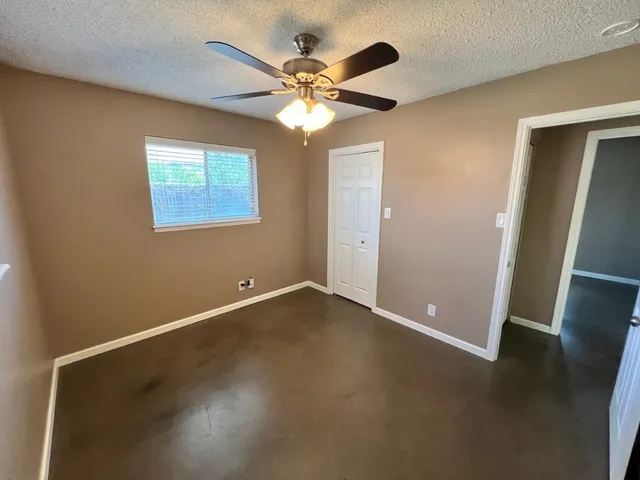 an empty room with wooden floor fan and window