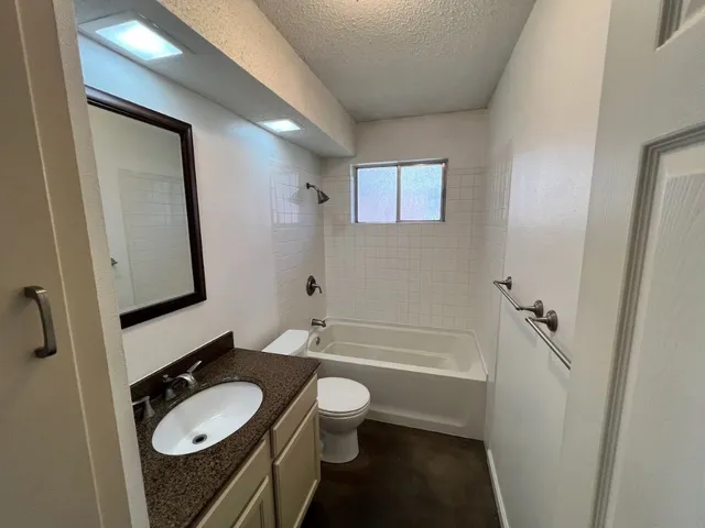 a bathroom with a granite countertop sink toilet mirror and bathtub