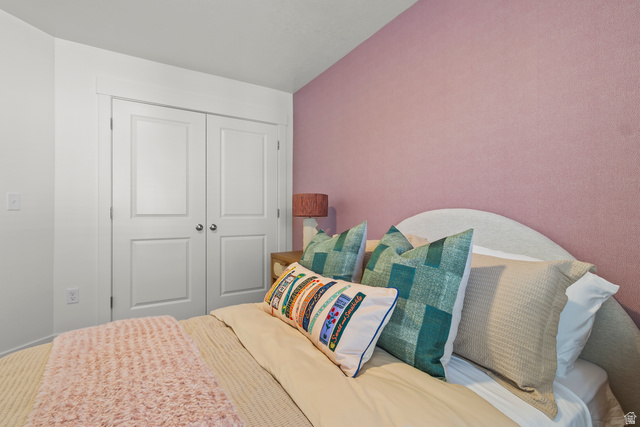 3074 South 270 West Logan, UT 84321 - Photo 20 of 30 White bi-fold closet doors with panel detailing, textured pink wall, and a curved headboard
