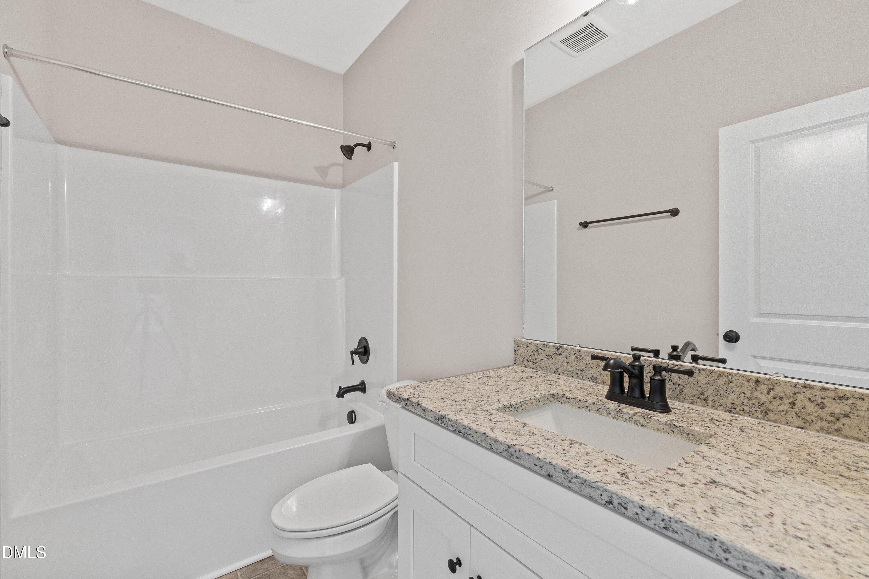 1061 Nor-Am Road Pikeville, NC 27863 - Photo 33 of 39 a bathroom with a granite countertop sink a toilet and a bathtub