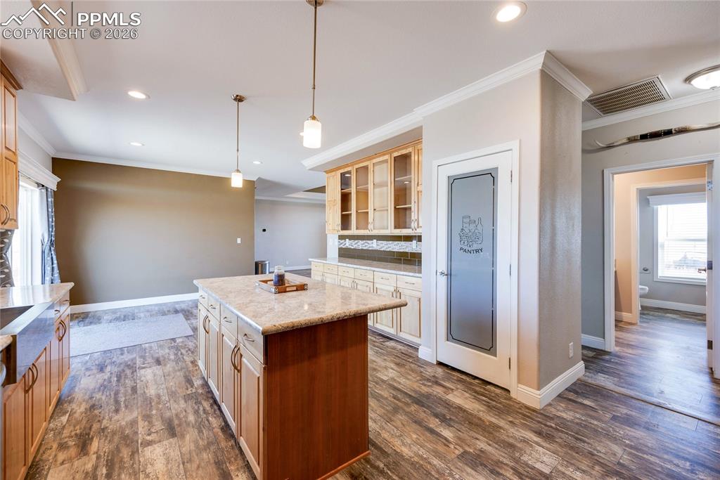 7880 J D Johnson Road Peyton, CO 80831 - Photo 15 of 50 Kitchen featuring healthy amount of natural light, ornamental molding, decorative light fixtures, glass insert cabinets, and a center island