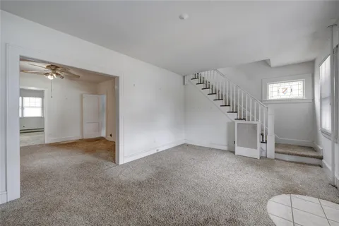 a view of an empty room with stairs and a living room