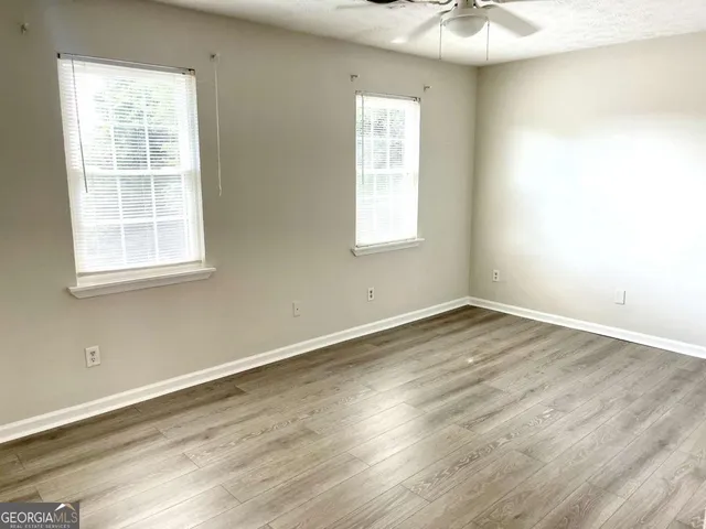 an empty room with wooden floor and windows