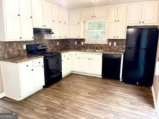 a kitchen with granite countertop a refrigerator stove top oven and sink