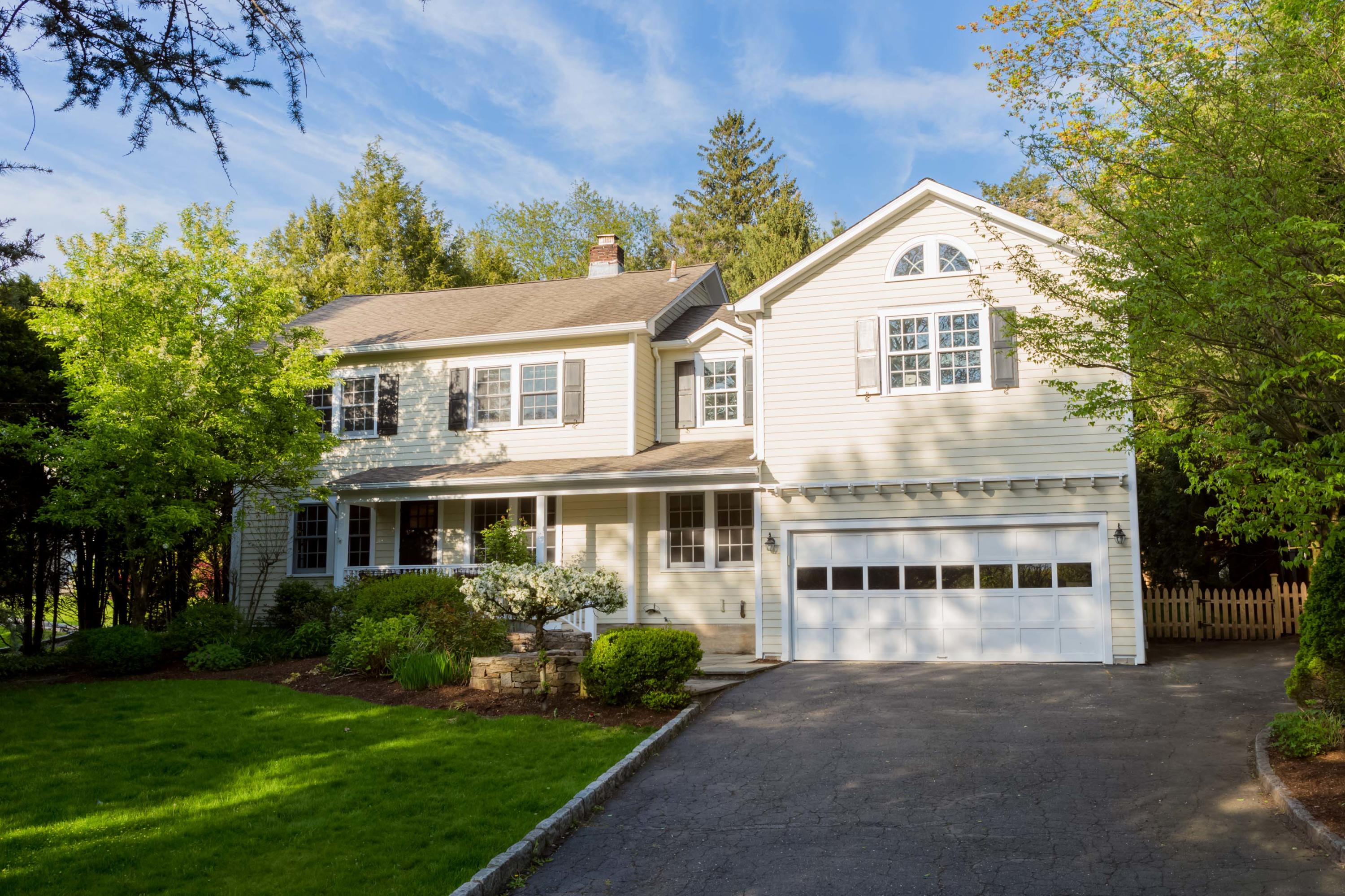 a view of a white house with a big yard and large trees