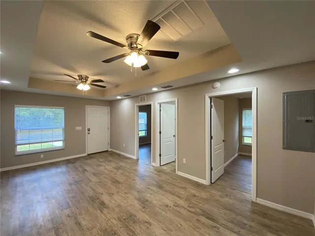 a view of an empty room with wooden floor and a ceiling fan