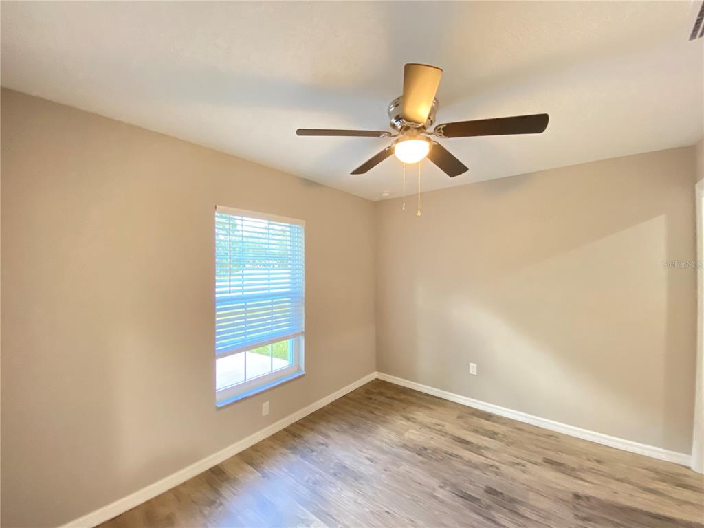 8950 North Mendoza Way Citrus Springs, FL 34434 - Photo 19 of 35 an empty room with wooden floor fan and windows