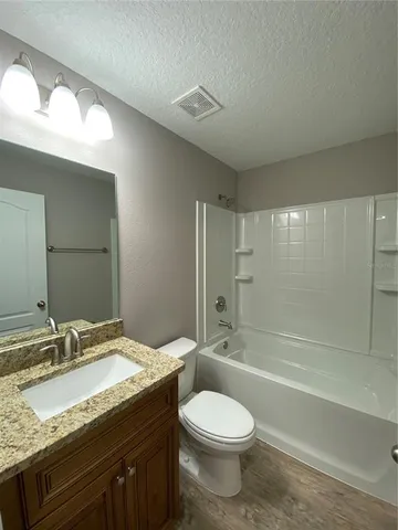 a bathroom with a granite countertop sink toilet and shower