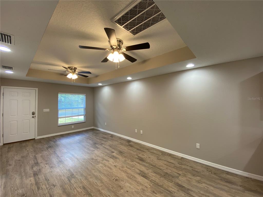 8950 North Mendoza Way Citrus Springs, FL 34434 - Photo 4 of 35 an empty room with wooden floor chandelier fan and windows