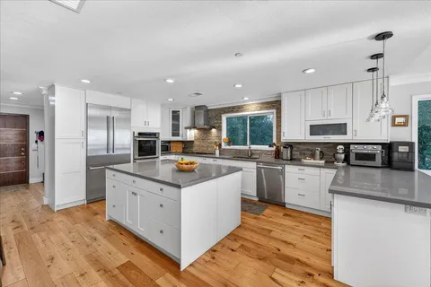 a kitchen with stainless steel appliances granite countertop a stove top oven a refrigerator a sink and dishwasher