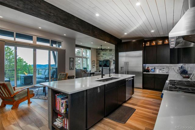 a large kitchen with stainless steel appliances granite countertop a large stove a sink dishwasher and a dining table with the garden view