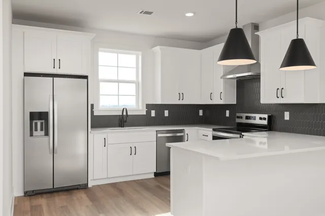 a kitchen with stainless steel appliances a refrigerator a sink a stove a microwave and cabinets