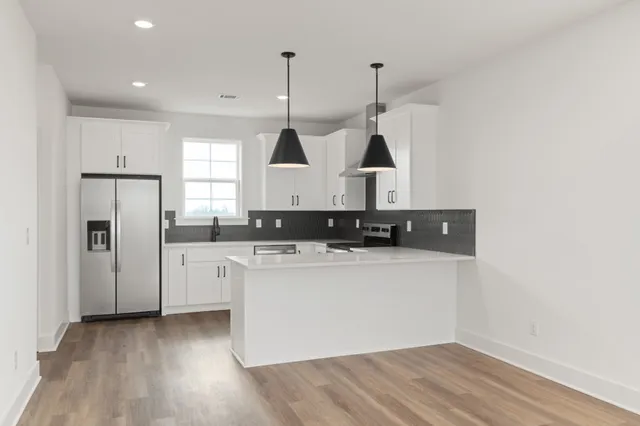 a kitchen with stainless steel appliances granite countertop a sink a stove a refrigerator and island with wooden floor