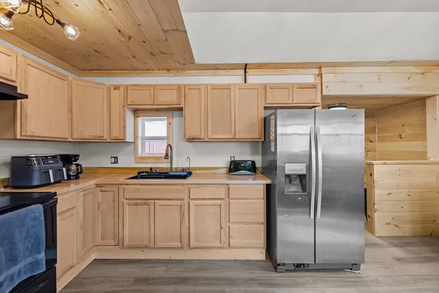 a kitchen with stainless steel appliances granite countertop a refrigerator a sink and white cabinets