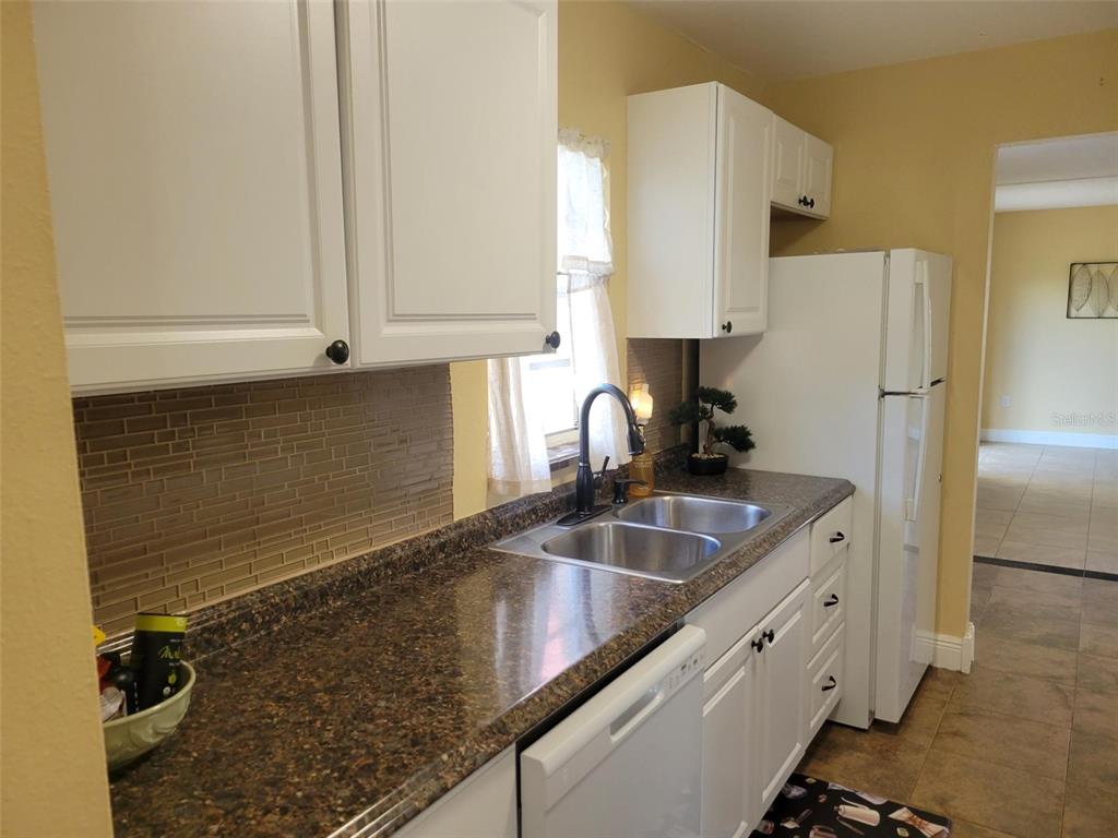 10032 65th Avenue North, Unit 8 St. Petersburg, FL 33708 - Photo 32 of 61 a kitchen with granite countertop a sink a counter top space cabinets and stainless steel appliances