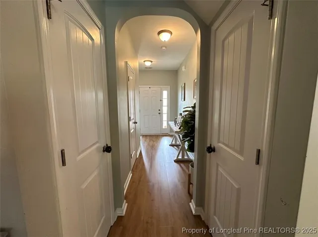 a view of a hallway with wooden floor and a bathroom