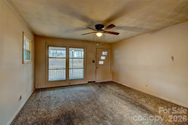 an empty room with chandelier fan and windows