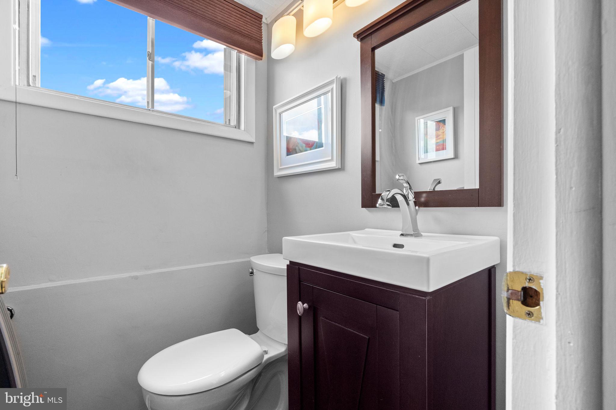 3166 Hulmeville Road Bensalem, PA 19020 - Photo 25 of 40 a bathroom with a toilet a sink a mirror and a window