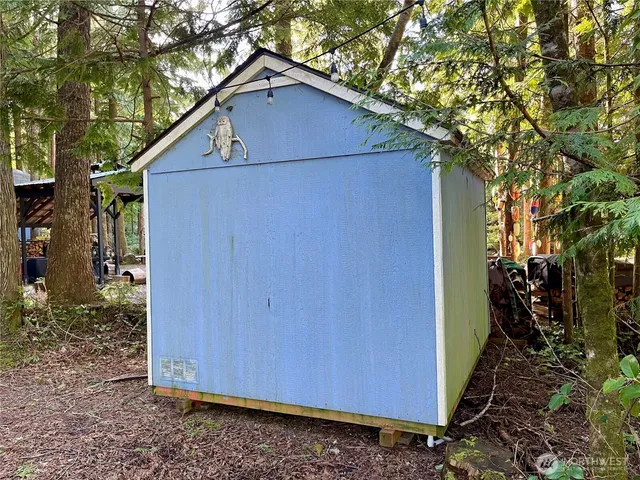 a view of a small barn in the backyard with large tree