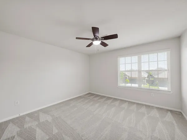 an empty room with a window and a fan