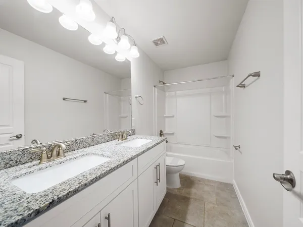 a bathroom with a granite countertop sink a toilet and bathtub