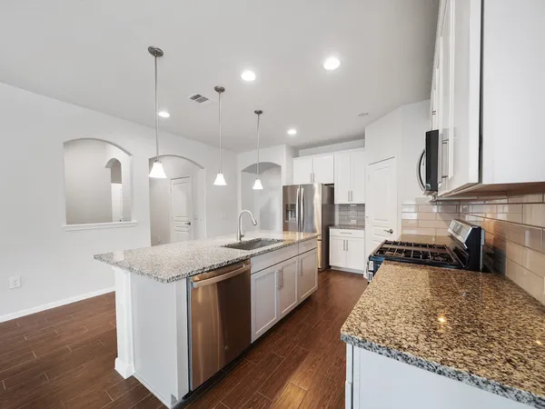a kitchen with stainless steel appliances granite countertop sink stove and wooden floor