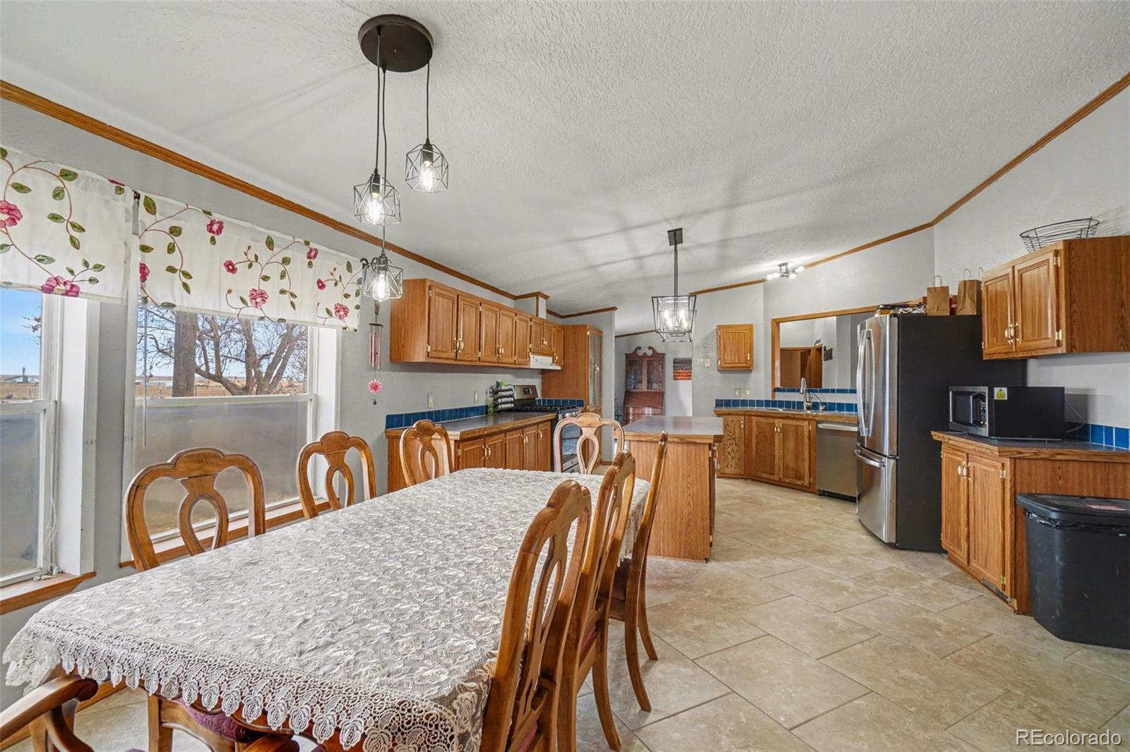 8260 County Road 39 Fort Lupton, CO 80621 - Photo 7 of 32 a kitchen with stainless steel appliances granite countertop a stove a sink a dining table and chairs with the wooden floor