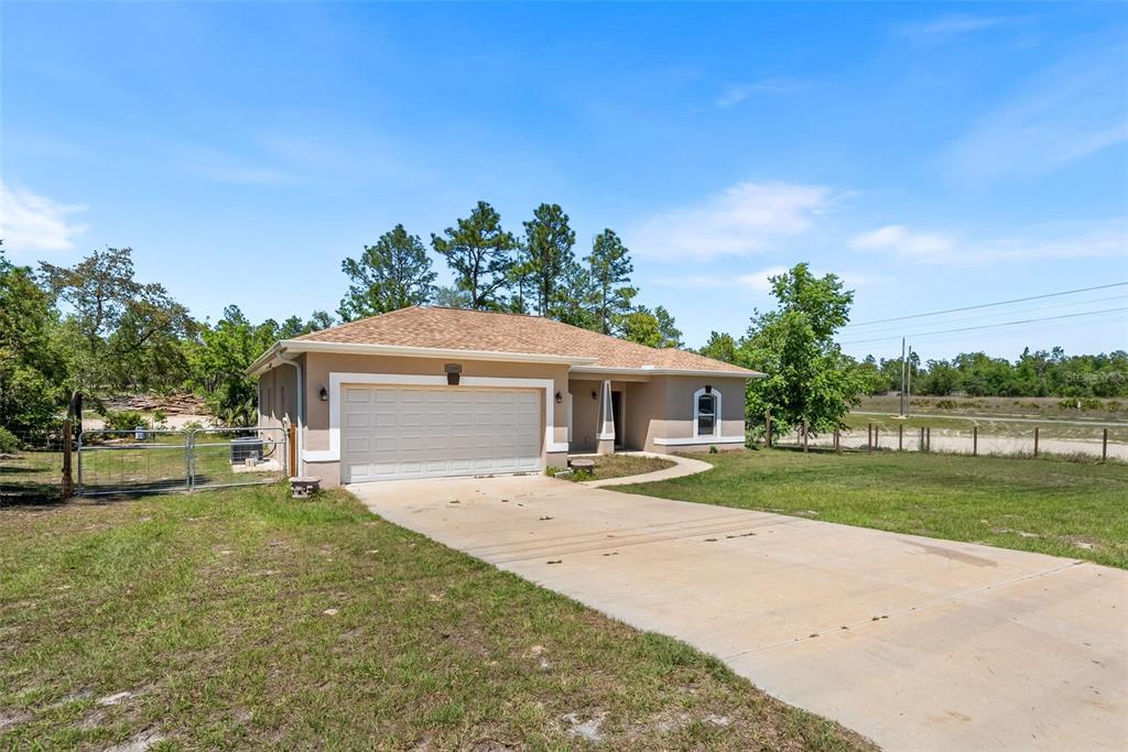 13391 Ruffed Grouse Road Weeki Wachee, FL 34614 - Photo 2 of 25 a front view of a house with a yard and garage