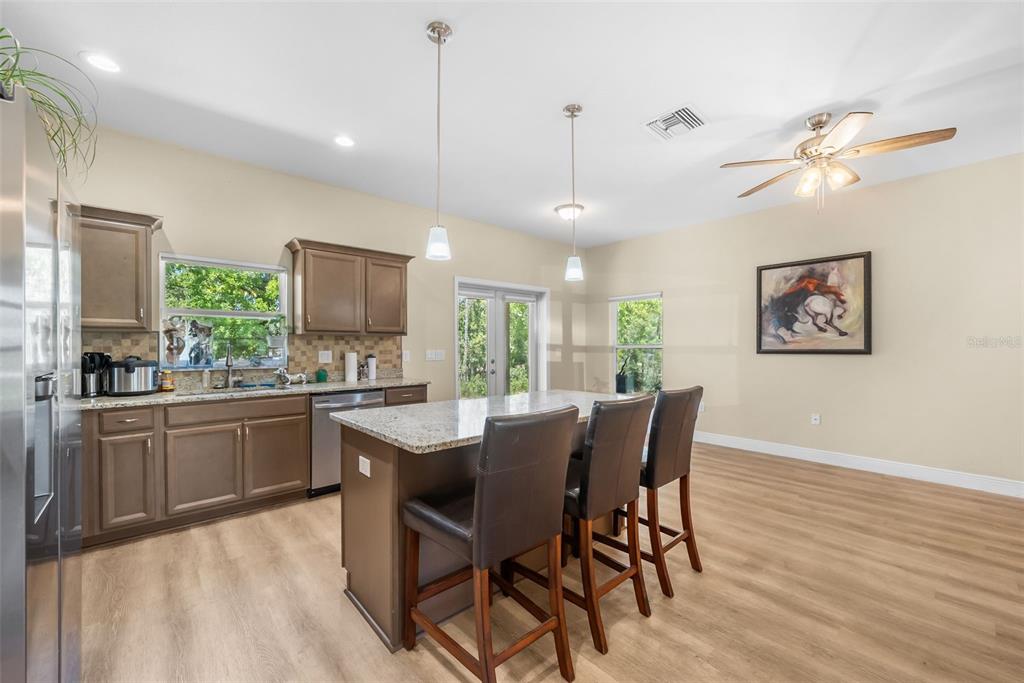 13391 Ruffed Grouse Road Weeki Wachee, FL 34614 - Photo 7 of 25 a kitchen with kitchen island a dining table chairs stainless steel appliances and cabinets