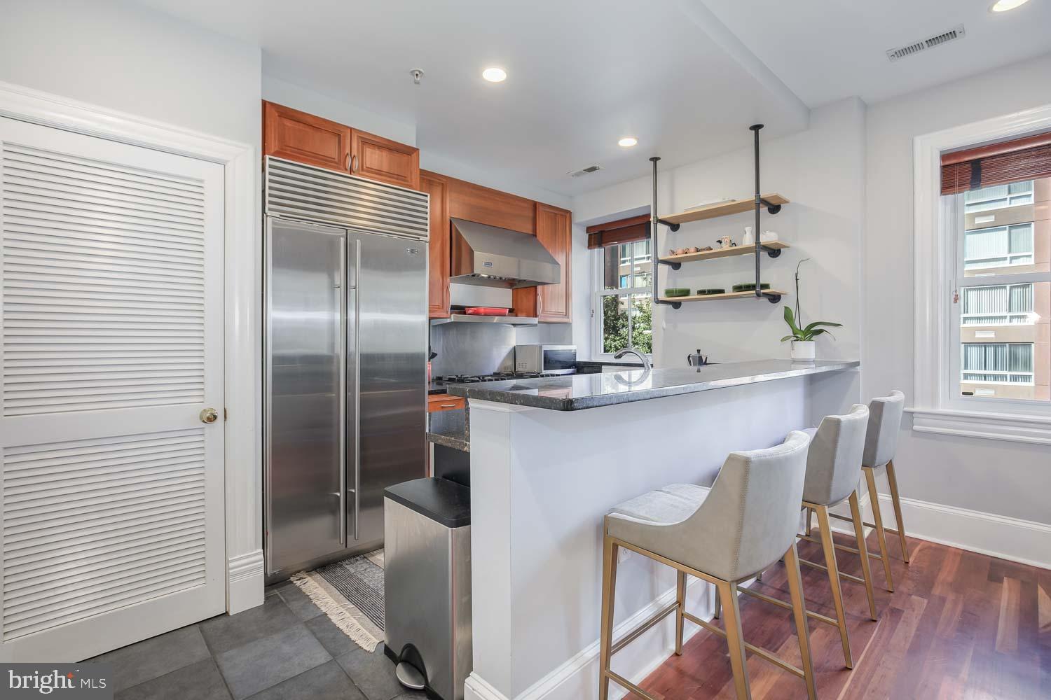 1212 M Street Northwest, Unit 401 Washington, DC 20005 - Photo 5 of 16 a kitchen with kitchen island white cabinets a refrigerator and a dining table