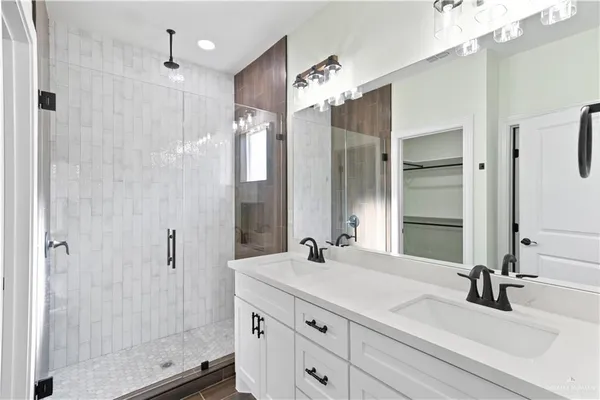 a bathroom with a double vanity sink mirror and shower