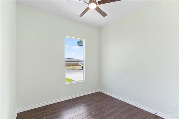 an empty room with wooden floor chandelier fan and windows