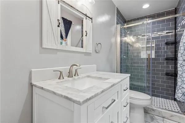a bathroom with a granite countertop sink toilet and shower