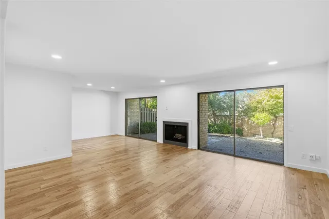 a view of an empty room with wooden floor and a fireplace