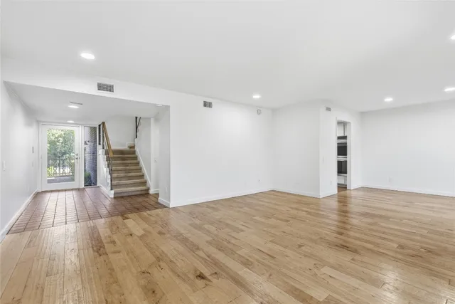 a view of an empty room with wooden floor and stairs