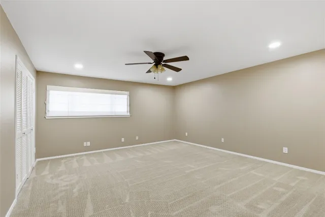 a view of an empty room with a ceiling fan and window