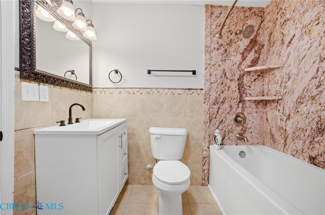 733 Spruce Street Hampton, VA 23661 - Photo 20 of 29 Bathroom featuring vanity, tile walls, shower / tub combination, a wainscoted wall, and light tile patterned floors