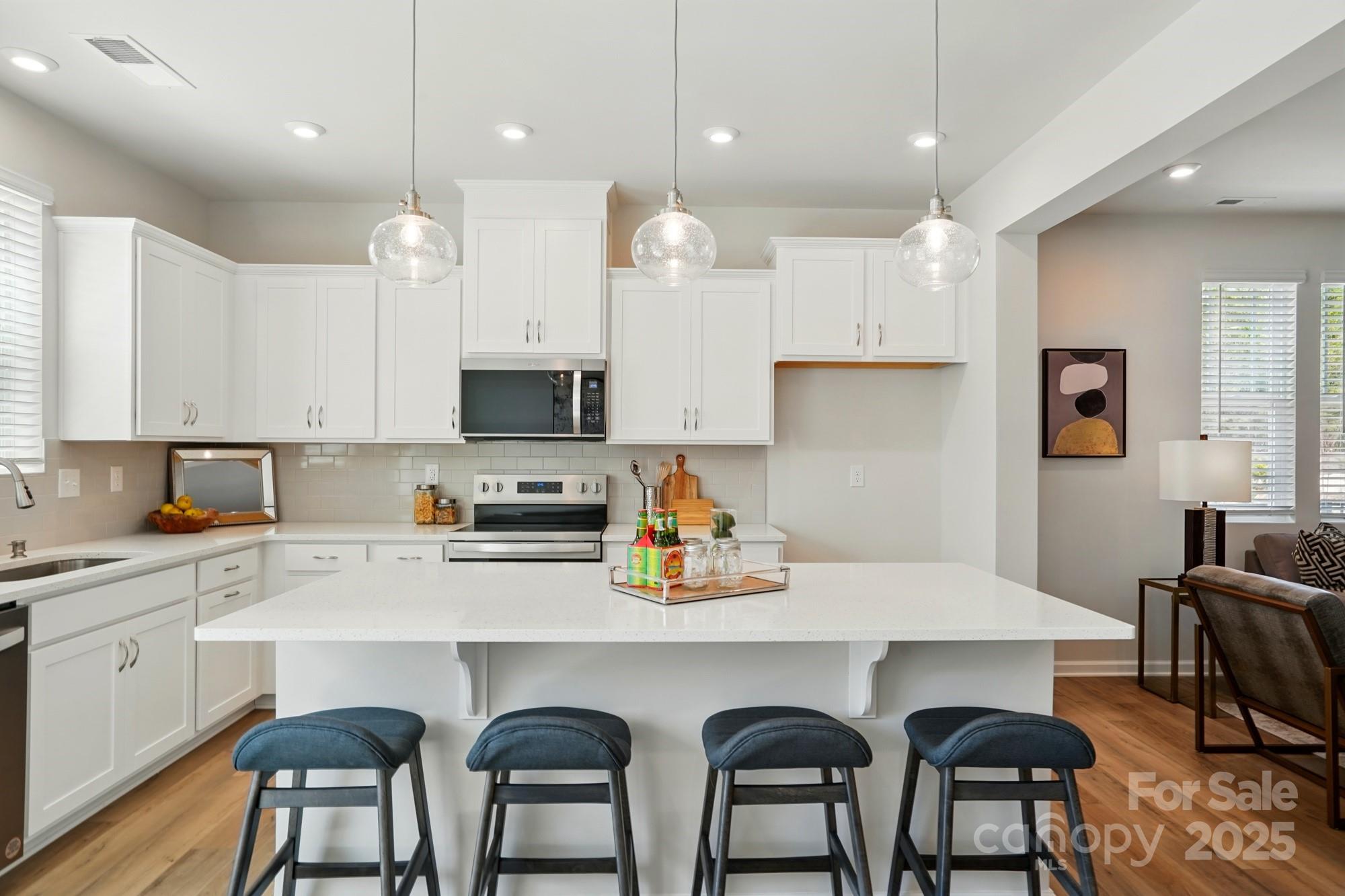 a kitchen with stainless steel appliances a dining table chairs sink refrigerator and microwave