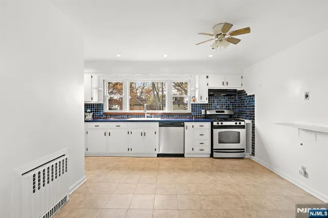 a kitchen with stainless steel appliances a stove top oven a sink a window and a refrigerator