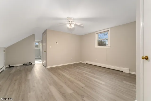 an empty room with wooden floor chandelier fan and windows