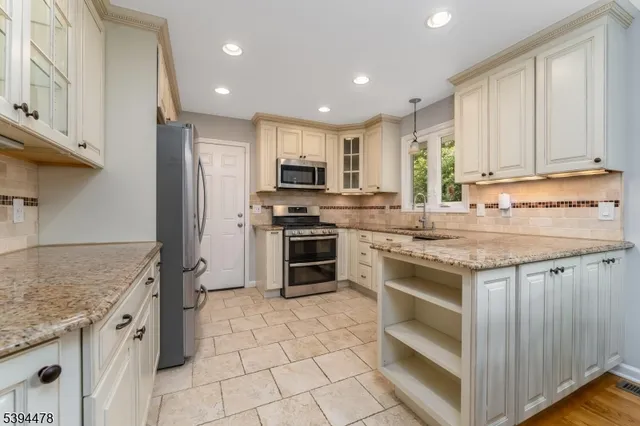 a kitchen with stainless steel appliances granite countertop a stove a sink and a refrigerator