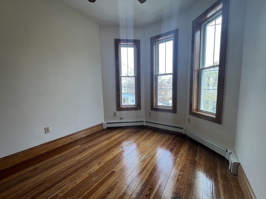 18 Houghton Street, Unit 1 Somerville, MA 02143 - Photo 9 of 13 a view of an empty room with wooden floor and a window